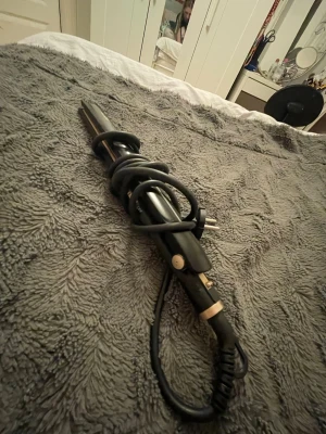 Locktång och plattång i svart - Säljer ett set med en svart locktång och en svart plattång. Båda har sladd och är tillverkade i plast och metall. Plattången har keramiska plattor och locktången har en smal cylinderformad stav. Perfekt för att styla håret med olika looks.