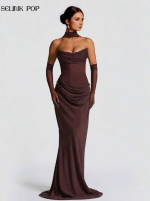 Brun långklänning från Selink Pop - Elegant brun långklänning med draperad överdel och avtagbara meshhandskar. Klänningen har en axelbandslös design, markerad midja och mjukt fallande tyg som ger en lyxig känsla. Matchande halsband i samma material ingår.