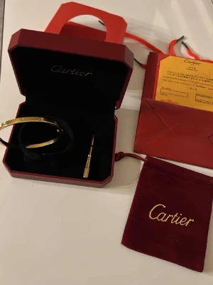 Love armband i guld - Säljer ett ikoniskt C.artier Love armband i härdat stål , skruvmejsel och certifikat. Klassisk oval form med skruvdetaljer runt om. Perfekt för dig som gillar exklusiva accessoarer.