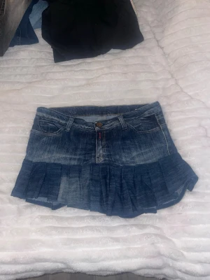 Jeanskjol med volangkant - Snygg blå jeanskjol från Gangsta med volangkant nedtill. Kjolen har klassiska jeansdetaljer som fickor fram och bak, bälteshällor och knappstängning. Perfekt för dig som gillar en trendig och ungdomlig stil.