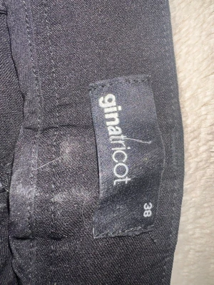 Svarta kostymbyxor från Gina Tricot - Snygga svarta kostymbyxor från Gina Tricot i storlek 38. Klassisk rak passform med normal midja och bälteshällor. Materialet känns mjukt och stretchigt, vilket gör dem bekväma att bära hela dagen.