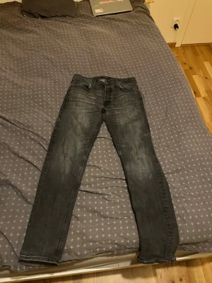 Mörkgrå slim fit jeans - Säljer ett par mörkgrå slim fit jeans med klassisk femficksdesign och snygga slitningar. Jeansen har raka ben och är tillverkade i denim med stretch för extra komfort. Perfekta för dig som gillar en stilren och modern look.
