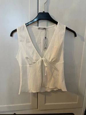 Vit linnetopp med knyt - Snygg vit linnetopp med v-ringning och knyt framtill. Toppen har tyvärr inte kommit till användning då jag köpte den till utlandsresa men sedan glömt av den. Den passar perfekt till en fin sommardag eller en utomlands resa! Pris kan diskuteras. OBS! Köparen står för frakt