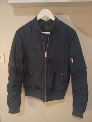 Mörkblå bomberjacka från Crocker - Trendig mörkblå bomberjacka från Crocker. Storlek S. Lite fodrad jätteskön och i mycket bra skick 