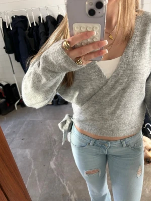 Grå omlottstickad tröja - Säljer en ljusgrå omlottstickad tröja med knyt i sidan. Inspirerad av &OtherStories tröjan.