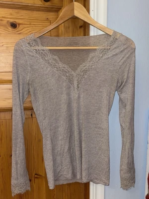 Beige långärmad topp från Intimissimi - Superskön beige långärmad topp från Intimissimi med v-ringning och spetsdetaljer vid halsringning och ärmslut. Tillverkad i en mjuk blandning med kashmir som känns lyxig och tunn mot huden. Perfekt nu inför vår och sommar! Nästan helt oanvänd!