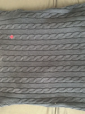 Navy stickad tröja - Mysig navyblå stickad tröja med klassiskt kabelstickat mönster i breda ränder. Tröjan har en liten röd detalj på framsidan och är perfekt för kyligare dagar. Passar dig som gillar enkel men snygg stil.