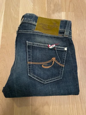 Jacob Cohen mörkblå jeans, strl 27 - Jättesnygga mörkblå jeans från Jacob Cohen i storlek 27 |Jättefint skick inga skador eller hål. |Nypris ca 5000 kr mitt pris endast 599kr | Fraktar inom 24 timmar med instabox, bring eller PostNord | Typbiten där bak är designad av Jacob Cohen och representerar de italienska färgerna | Mått: Längd: ca 100 cm | Bredd: (vid midjan från sida till sida) ca 35 cm, måtten kan vara fel med 1+\- | vid fler frågor eller funderingar, vänligen kontakta mig 😃