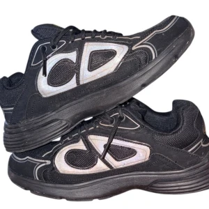 Svarta sneakers med reflekterande detaljer - Säljer ett par svarta sneakers med reflekterande silvriga detaljer och tjock sula. Skorna har en sportig look med mesh och syntetmaterial, samt snörning framtill. Perfekta för dig som gillar streetwear och vill sticka ut.