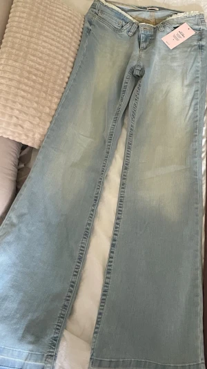 Ljusblåa vida jeans med rå kant - Säljer ett par blå bootcut jeans storlek 36 lågmidjade, helt nya fick hem dom idag men tyvärr för stora därav säljer jag dom, nerpackade i påsen igen redo att skickas. Nypris-599kr mitt pris 450kr