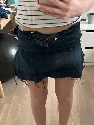 Mörkblå jeans/volangkjol - Säljer min egengjorda jeans/volang kjol. Mörkblå kjol med två volang-rader, ganska högmidja men jag brukar vika ner kanten så den blir lågmidjad. Inte noggrant gjort utan för skoj skull hemma vilket gör den lite cool och vintage. Säljer endast för att den är lite för liten för mig och bara ligger hemma i garderoben. Jeansen från början är i storlek XS och den är ganska liten.