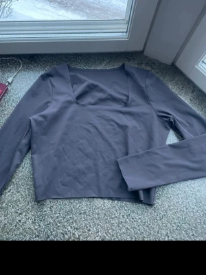 Tränings top från ICANIWILL - Snygg grå/brun långärmad tränings top från ICANIWILL med fyrkantig ringning. Tillverkad i ett stretchigt och mjukt material som passar perfekt till träning eller chill. Diskret ICW-logga framtill vid halsen. 