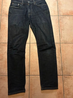 Levi's 502 mörkblå jeans - Säljer ett par Levi's 502 jeans i mörkblå tvätt med klassiska fem fickor och snygga kontrastsömmar. Jeansen har en taper passform och är tillverkade i slitstarkt denim. Perfekta för dig som gillar en tidlös och clean look. Tar emot frågor o bud!