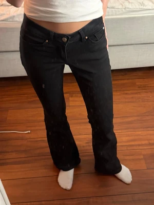 Svarta bootcut jeans med låg midja - Säljer ett par svarta bootcut jeans med låg midja. Jeansen har en snygg, figurnära passform upptill och lätt utsvängda ben. Perfekta till sneakers eller boots och passar till många olika stilar.