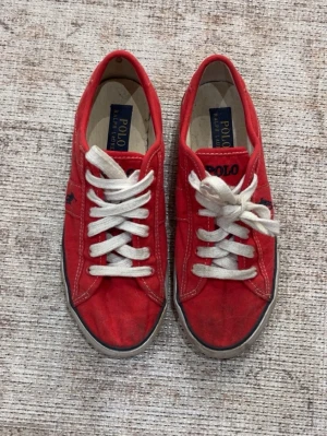 Ralph Lauren sneakers  - Snygga röda vintage sneakers från Polo Ralph Lauren med vita snören och klassisk låg profil. Skorna är lite smutsiga framtill men inget som inte går bort i tvätten!