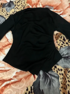 Svart långärmad topp - Snygg svart långärmad topp med figurnära passform och enkel design. Perfekt att styla med jeans eller kjol för en clean look. Materialet känns mjukt och stretchigt, vilket gör den bekväm att bära hela dagen. Oanvänd. 