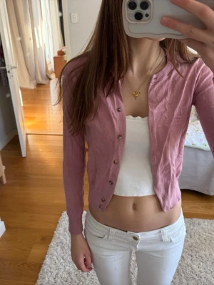 Ljuslila kofta med knappar - Söt ljuslila kofta med rund halsringning och långa ärmar. Koftan har stilrena silverfärgade knappar framtill och ribbade muddar vid ärmslut och nederkant. Perfekt att styla över ett linne eller t-shirt för en trendig look.