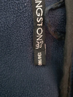 Marinblå quiltad jacka Kingsland - Snygg marinblå jacka från Kingsland med quiltade partier framtill och röda dragkedjor. Jackan har huva, långa ärmar och sportig look. Perfekt för dig som gillar stilrena detaljer och funktionell design.