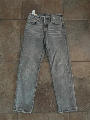Grå raka jeans i vintage-look - Säljer ett par grå jeans med rak passform och klassisk femficksdesign. Jeansen har en snygg tvättad vintage-look och är tillverkade i denim. Perfekta för dig som gillar en avslappnad och tidlös stil.