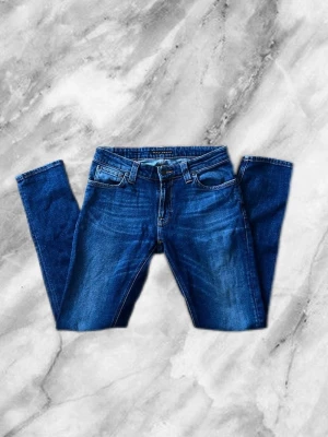 Blå slim fit jeans med stretch - Säljer dessa nudie jeans för att de bara sitter i mitt garderob och de är ej mitt still längre.  Säljer de för billigt pris för att jag vill inte att de ska sitta i mitt garderob och samla damm. Köpte av en polare för 1300 kr (ny pris 2000 kr) och jag säljer de för 750 kr. Pris kan diskuteras. Vid intresse eller frågor får du gärna skicka ett sms eller buda.