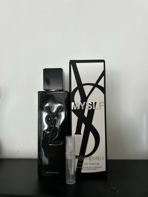 YSL MYSLF Eau de Parfum 2ml - Snygg parfym från Yves Saint Laurent, MYSLF Eau de Parfum. Flaskan är svart med stor YSL-logga i relief och har en stilren, fyrkantig form. Medföljer originalkartong i svartvitt och en liten genomskinlig provflaska. Säljer 2ml där pris kan diskuteras.