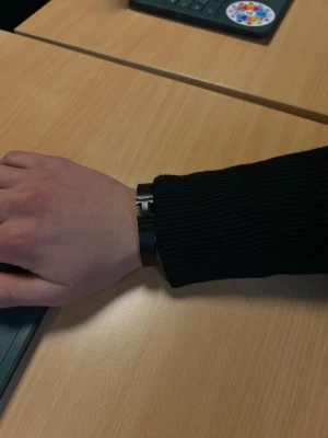 Svart metallarmband med H-detalj - Snyggt svart armband i metall med en stilren H-formad detalj i silverfärg. Armbandet har en modern och minimalistisk design som passar perfekt till olika outfits. Lätt att ta på och av tack vare det smidiga spännet.