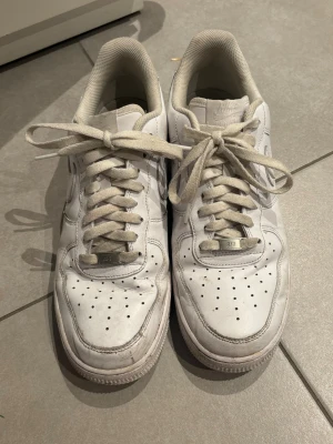 Vita Nike Air Force 1 sneakers - Klassiska vita Nike Air Force 1 sneakers, vita skosnören, perfekta för en clean streetwear-look.