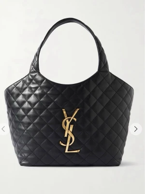 Svart väska från YSL - Säljer en svart väska från Yv Saint Laurent med ikoniskt guldigt YSL-emblem framtill. Väskan är tillverkad i läder och har en rundad form med breda handtag. Medföljer en matchande mindre clutch i samma material och mönster. Pris kan diskuteras 