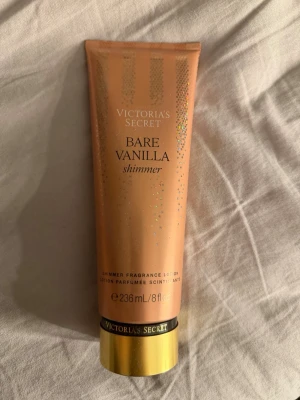 Victoria's Secret Bare Vanilla Shimmer -  En helt ny Shimmer lotion från Victoria's Secret i doften Bare Vanilla. Tuben är guld- och beige-färgad med glittriga detaljer och rymmer 236 ml. Ger huden en skimrande finish och doftar vanilj och mjuk kashmir. Perfekt för dig som vill ha både återfuktning och glow.