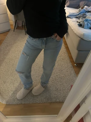 Ljusblå raka jeans med slitningar - Säljer ett par ljusblå jeans med raka ben och slitningar på ena låret och knät. Jeansen har klassisk femficksmodell och hög midja. Storlek 34🌸🌸