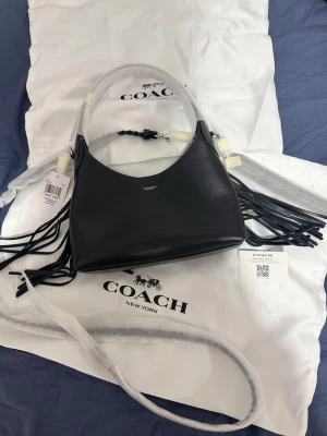 Coach Brooklyn 23 väska  - Helt ny Coach-väska modell Brooklyn 23 Naturligt lader Invändig multifunktionsficka Magnetisk tryckknappsstangning Handtag med 18,5 cm fall Avtagbar rem med 61 cm längd för att bära på axeln eller crossbody. 23,5 cm (L)x18,5 cm (H) x 7,5 cm (B) 