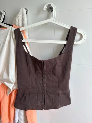 Brun korsettopp från Bershka - Brun korsett topp. Endast testad och därav deo fläckar. Slutsåld på hemsidan.