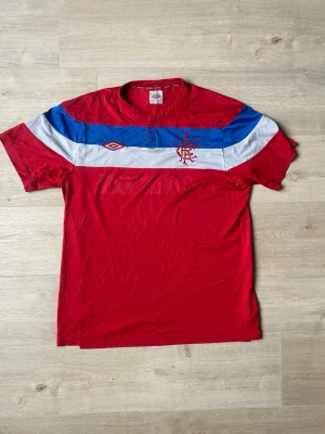 Röd Rangers FC Umbro Bortatröja 2011/12 Fotbollströja Storlek L - Mycket fin fotbollströja i röd färg. Tröjan är i mycket bra skick och sparsamt använda. |  Äkta som allt annat jag säljer! ✅ |  Storlek: L | Skick: Mycket Bra Skick | Färg: Röd | Märke: Umbro | Modell: Fotbollströja |   Hör gärna av dig vid frågor så svarar jag så fort jag kan! 😁