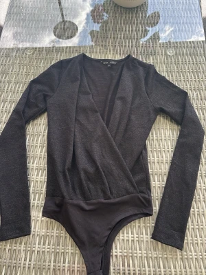 Svart body från ONLY - Säljer en svart body från ONLY med omlott-design och långa ärmar. Materialet är mjukt och stretchigt, perfekt för att skapa en snygg siluett. Bodyn har en djup v-ringning och klassisk stil som passar till många outfits. Använd 1 gång. 