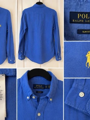 Blå linneskjorta från Polo Ralph Lauren - Snygg blå skjorta från Polo Ralph Lauren i linne med klassisk button-down krage och gul broderad logga på bröstet. Slim fit-modell med långa ärmar och vita knappar. Perfekt för en stilren och avslappnad look.