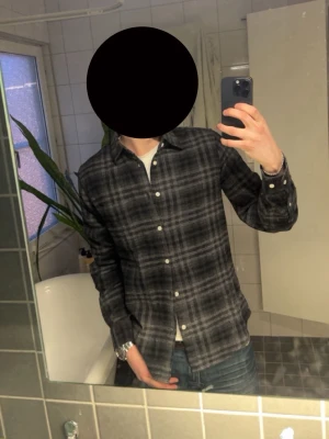 Gråmelerad rutig skjorta NN07 - Säljer en gråmelerad rutig skjorta från NN07 i storlek S. Skjortan har klassisk krage, knappar framtill och långa ärmar. Perfekt till jeans för en avslappnad men stilren look. Nästan helt ny 