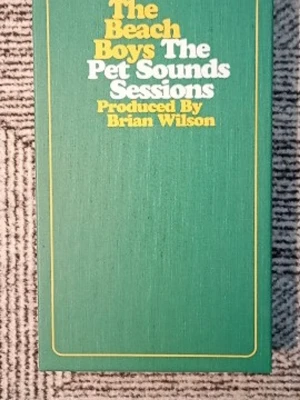 The Beach Boys Pet Sounds Sessions box - Säljer en samlarbox med titeln 'The Beach Boys The Pet Sounds Sessions', producerad av Brian Wilson. Boxen är grön med gul och vit text på framsidan och har insida med färgbilder av bandmedlemmarna i studiomiljö. Perfekt för musikälskare och samlare.