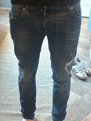 Blå slitna jeans från Tramarossa - Säljer ett par blå jeans från Tramarossa med snygga slitningar och tvättade detaljer på benen. Klassisk femficksmodell med smal passform och silverfärgad detalj på bakfickan. Modell:Leonardo slim