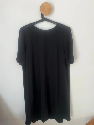 Svart klänning från COS - En stilren svart klänning från COS med enkel rak passform och korta ärmar. Klänningen har rund halsringning och dragkedja bak. Perfekt för dig som gillar minimalistisk design och tidlösa plagg.