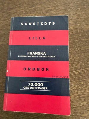 Norstedts lilla franska ordbok - En smidig och kompakt ordbok med röd och mörkblå randig mjukpärm. Innehåller 70 000 ord och fraser på franska och svenska, perfekt för studier eller resor. Tredje upplagan, lätt att ta med sig och använda.
