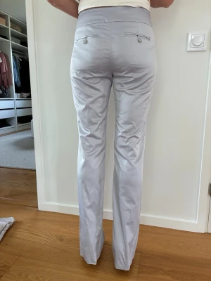 Ljus gråblå satin byxor stl 36 Nya - Ljust gråblå satin byxor från H&M stl 36. Byxor med raka ben och medelhög midja. Byxorna har fickor framtill och baktill. Försluts med dragkedja och hake framtill. Nya. Mkt bra passform.