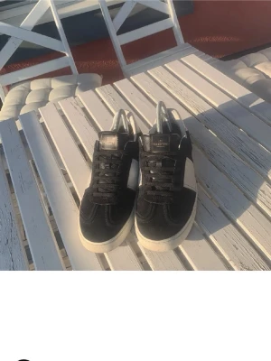 Svarta valentino flycrews - Snygga sneakers från Valentino i svart mocka och vitt läder. Klassisk låg modell med vita detaljer på sidan och vit sula. Skorna har svarta skosnören och en diskret logga på plösen. Perfekta för dig som gillar stilrena och exklusiva sneakers.