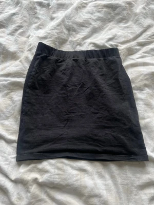 Svart kortkjol från FB Sister - Enkel svart kortkjol från FB Sister i mjukt bomullsmaterial. Kjolen har en rak passform med resår i midjan för extra komfort. Perfekt att matcha med en crop top eller hoodie för en chill look.