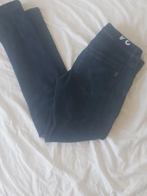 DonDup geoege - Snygga mörkblå jeans från DonDupmed klassisk femficksdesign och smal passform. Jeansen har diskret logga på bakfickan och är tillverkade i mjukt denimtyg med lite stretch för extra komfort.