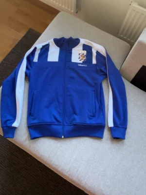 Blåvit IFK Göteborg träningsjacka Craft - Säljer en skitsnygg blå och vit träningsjacka från Craft med IFK Göteborgs klubbmärke på bröstet. Nypris ligger runt 1500 kr.Jackan har hel dragkedja, ståkrage och ribbade muddar. Perfekt för fotbollsträning eller som supporterplagg. Använd ca 4 gånger, skicket är som nytt. Hör av dig med prisförslag 