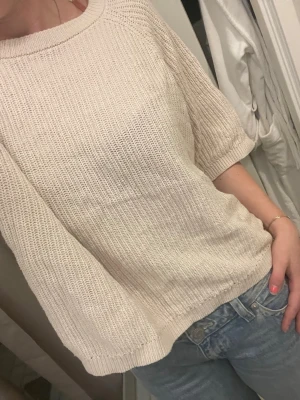 Beige stickad tröja med trekvartsärm - Säljer en stilren beige stickad tröja med rund halsringning och trekvartsärmar. Tröjan har en avslappnad passform och är stickad i ett mjukt material som passar perfekt till jeans eller kjol.