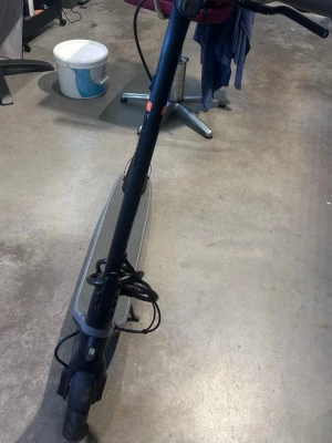 Svart elscooter Ninebot - Säljer en svart elscooter från Ninebot med grått handtag och display på styret. Scootern har en bred fotplatta med Ninebot-logga och robusta hjul. Perfekt för smidig transport i stan eller till skolan.