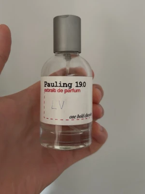 Pauling 19.0 extrait de parfum - Pauling 19.0 extrait de parfum från one bold chemist. Flaskan är genomskinlig med en enkel, modern design och har en grå spraykork. Etiketten är vit med svart och röd text. Parfymen är färglös och kommer i en rund glasflaska. Ungefär 40ml kvar