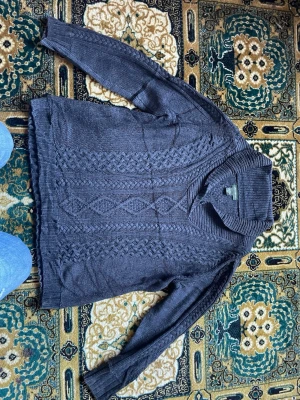 Mörkgrå stickad tröja Eddie Bauer - Snygg mörkgrå stickad tröja från Eddie Bauer med grov kabelstickning och bred sjalkrage. Tröjan har långa ärmar och ribbade muddar. Perfekt för dig som gillar klassisk och avslappnad stil. Materialet är mjukt och värmande.