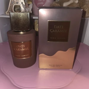 Date Caramel Eau de Parfum - Date Caramel Eau de Parfum från Paris Corner kommer i en lyxig brun flaska med räfflad yta och gulddetaljer. Doften har en söt och varm karaktär med inslag av karamell och dadlar. Perfekt för dig som gillar unika och gourmand-inspirerade parfymer.